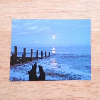 Postcard featuring unusual colours during an eclipse of the Moon on a beach