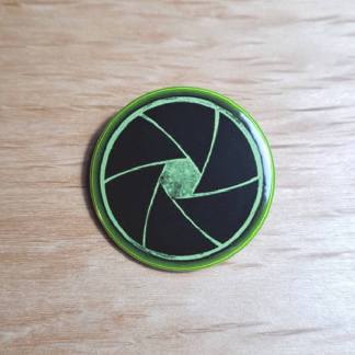 Badges and fridge magnets featuring a mechanical camera shutter