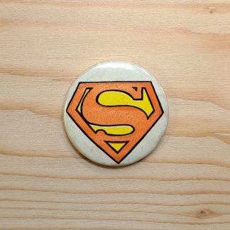 Vintage pin badge featuring the Superman shield logo